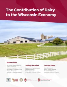 Modern dairy farm with white buildings, blue-roofed barns, grain silos, white fencing, and green pastures. Image is part of a report on dairy's contribution to the Wisconsin economy.