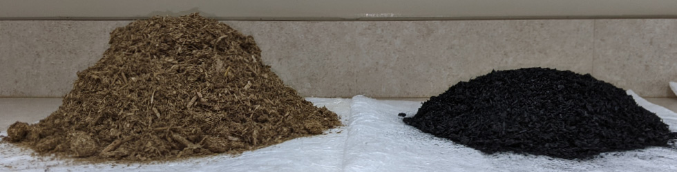 Two piles on white cloth: tan fibrous biomass feedstock (left) and black biochar (right), showing before and after pyrolysis.
